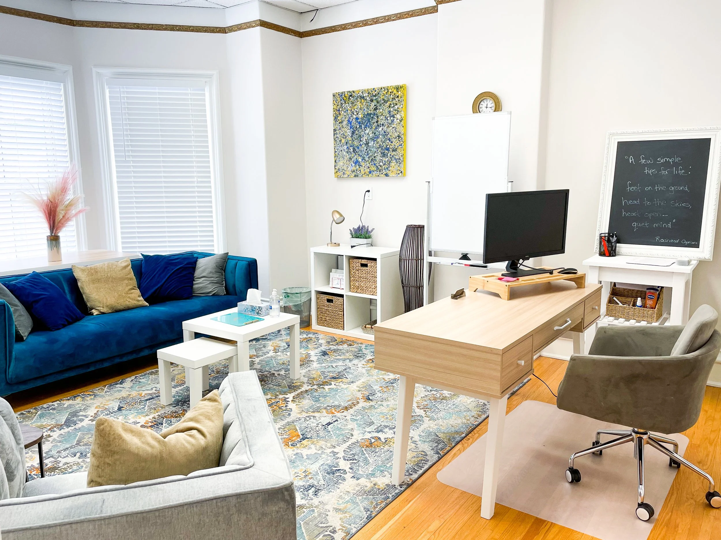 The Velvet Room at Lotus Counselling Services, a spacious therapy office with a blue velvet sofa, a desk, a whiteboard, and bay windows
