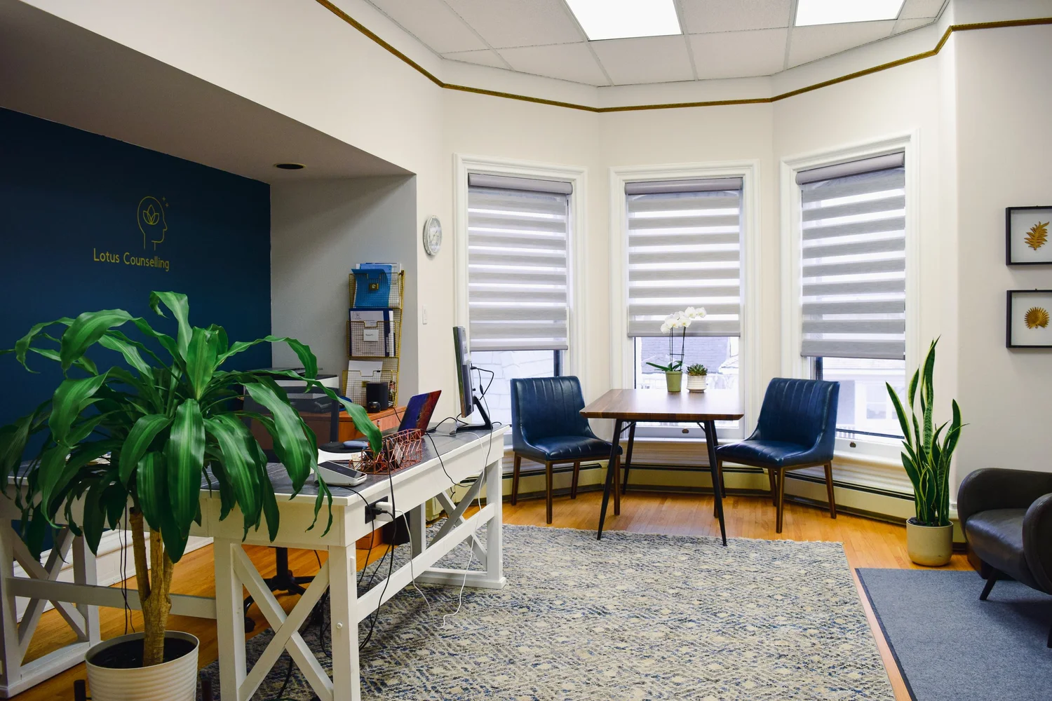 The waiting room at Lotus Counselling Services, a calm bay-window space with a sofa, armchair, and warm wood floors